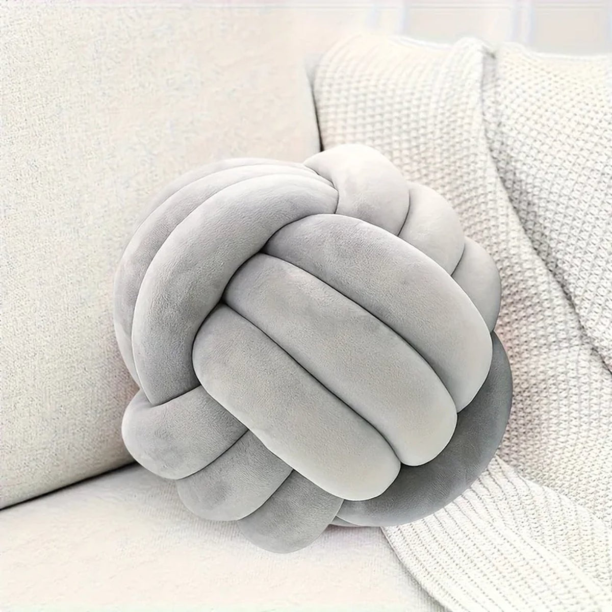 Détail du coussin nœud gris calé contre un accoudoir
