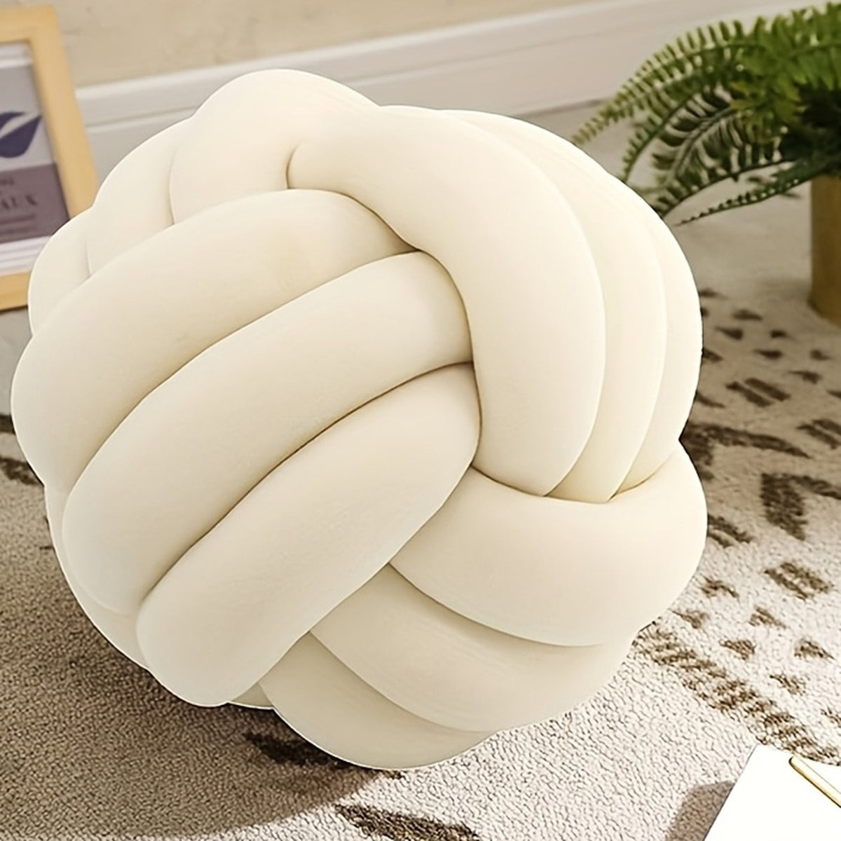 Détail du coussin nœud crème posé sur un tapis