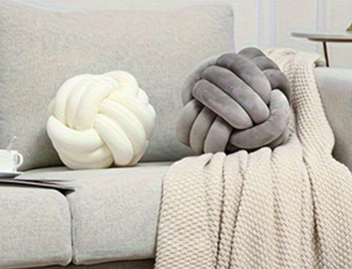Les deux coussins nœud, crème et gris, posés sur un canapé gris clair